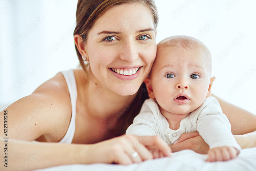 Portrait of happy and loving mother bonding with her cute baby boy at home while enjoying parenthood