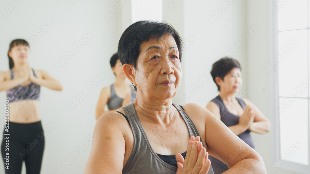 集团资深亚洲女性在健身房一起锻炼和练习瑜伽，健康高级概念