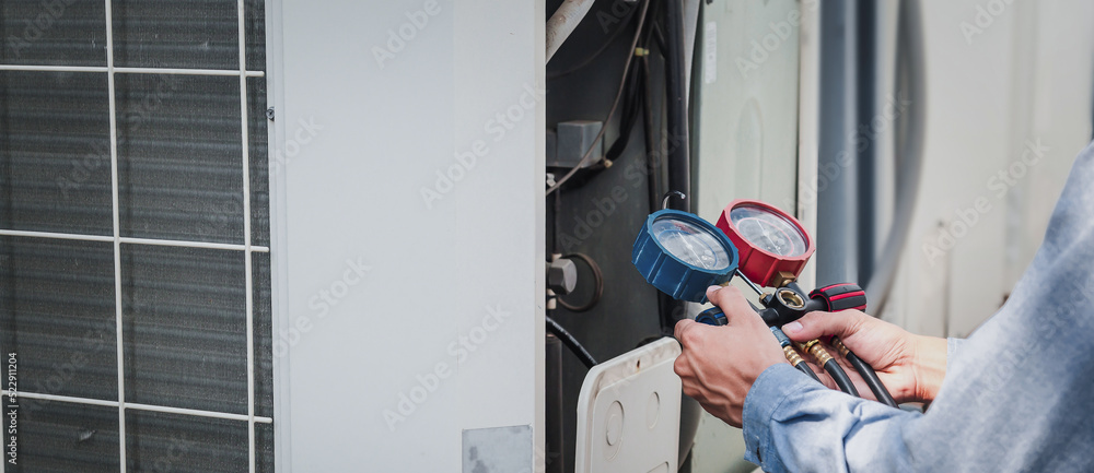 Mechanic  air conditioner technician is using a manifold gauge to check the refrigerant in the syste