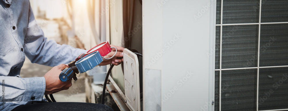 Mechanic  air conditioner technician is using a manifold gauge to check the refrigerant in the syste