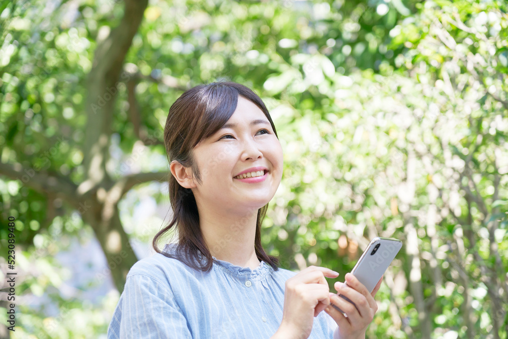 屋外で笑顔でスマホを使う女性