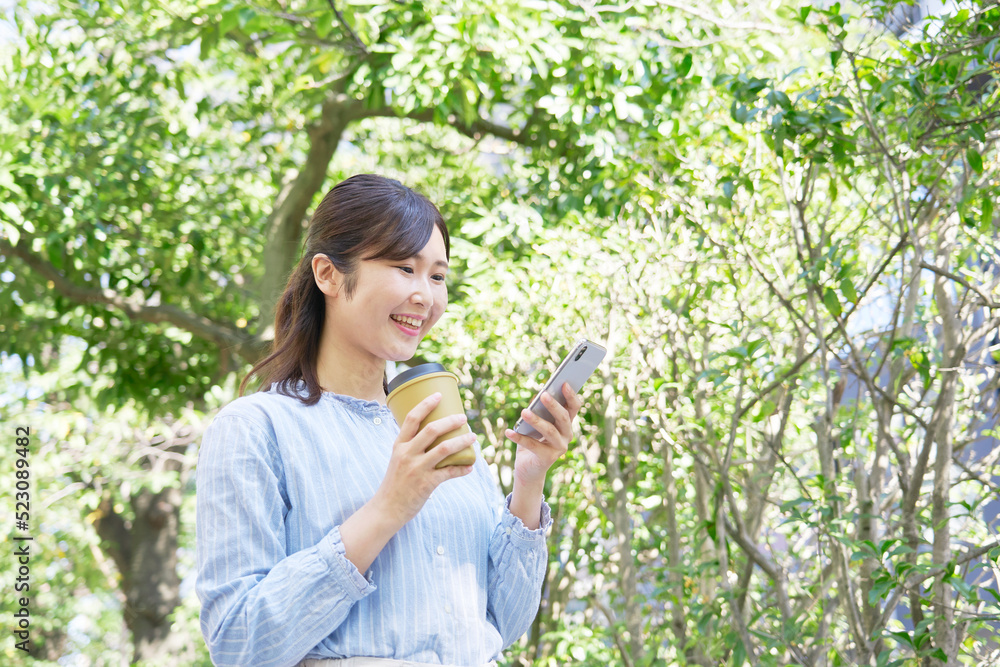 屋外で笑顔でスマホを使う女性