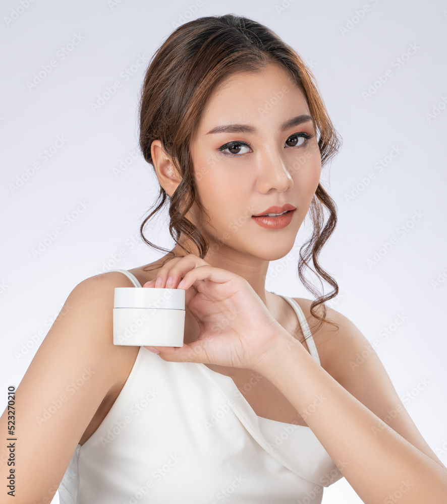 Gorgeous woman with makeup smiling holding mockup product for advertising text place, light grey bac