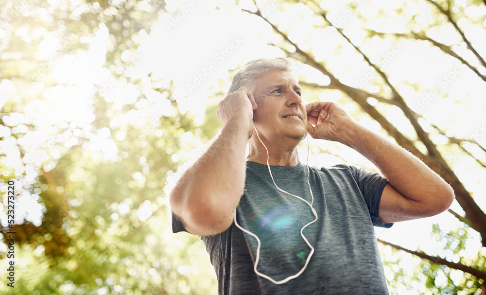 Healthy, fit and active senior man listening to music while running, exercising and training outside