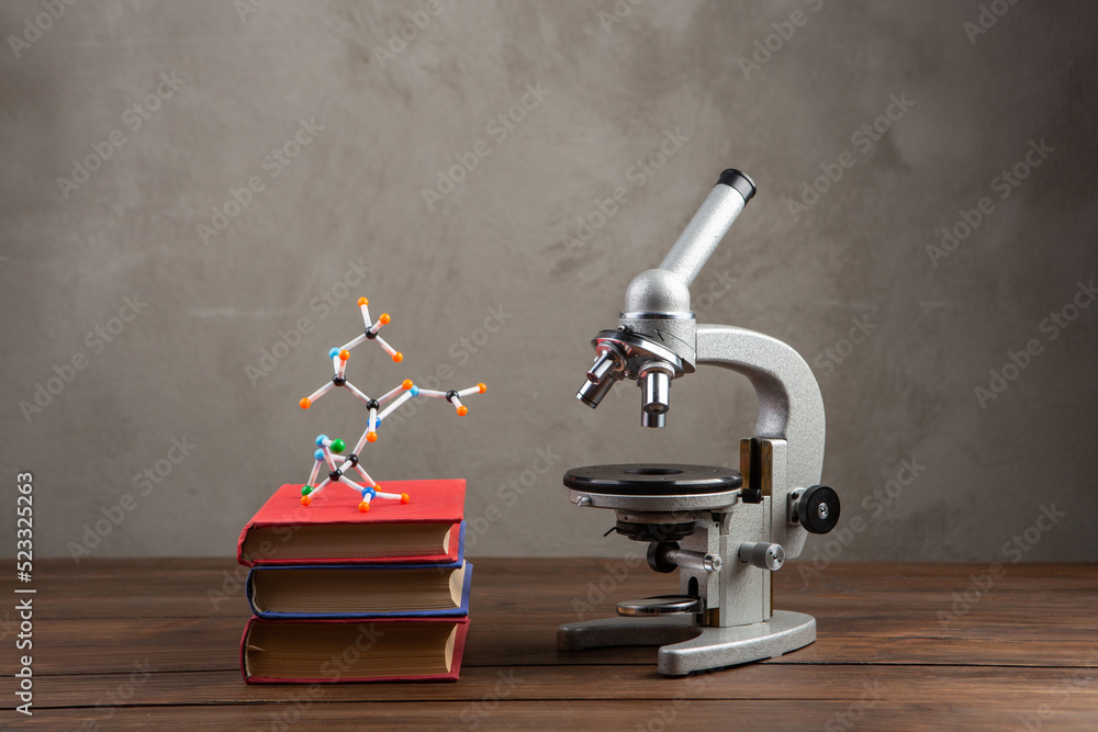 Back to school - books and microscope on the wooden desk in the auditorium, Education concept