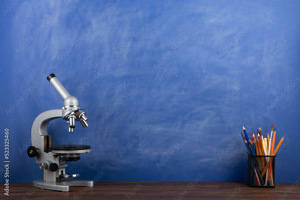 Back to school - microscope on the desk, Education concept. Blackboard background