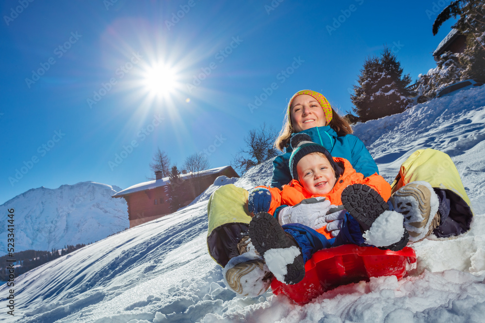 妈妈和小男孩一起坐在雪橇上下坡