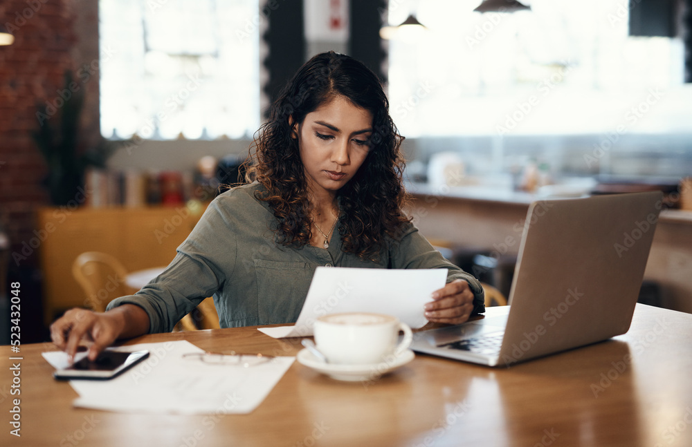 Young businesswoman, entrepreneur and coffee shop owner looking overwhelmed going through paperwork.