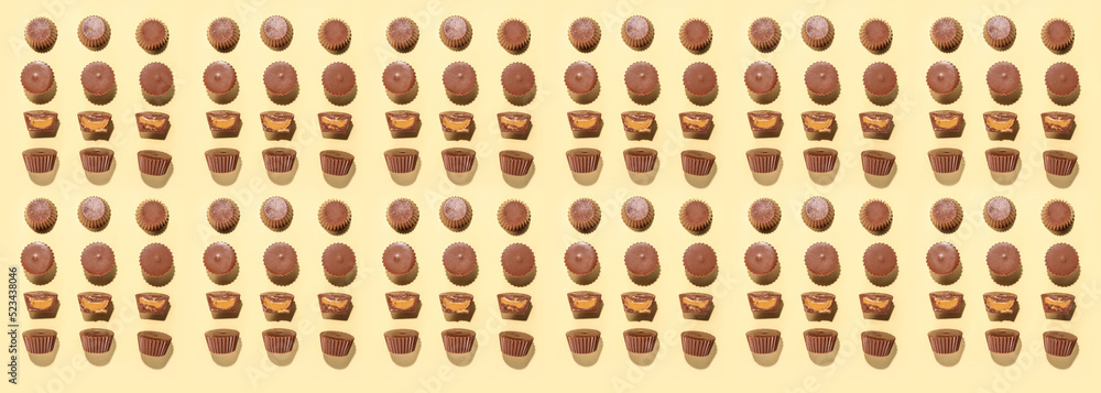 Tasty peanut butter cups on light background, top view