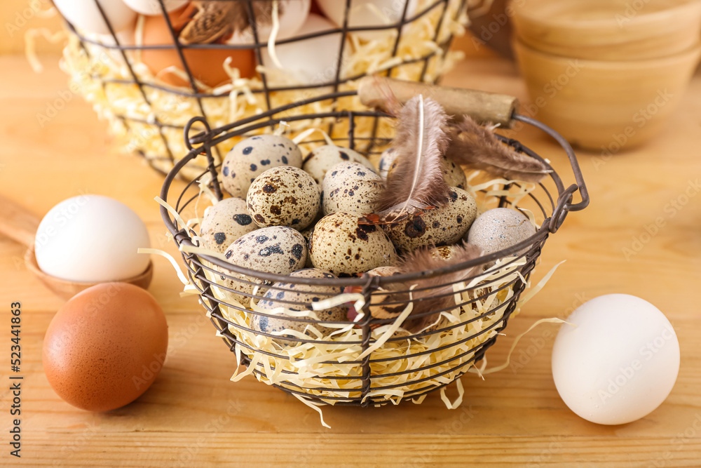 Basket of fresh quail eggs and feathers on wooden background