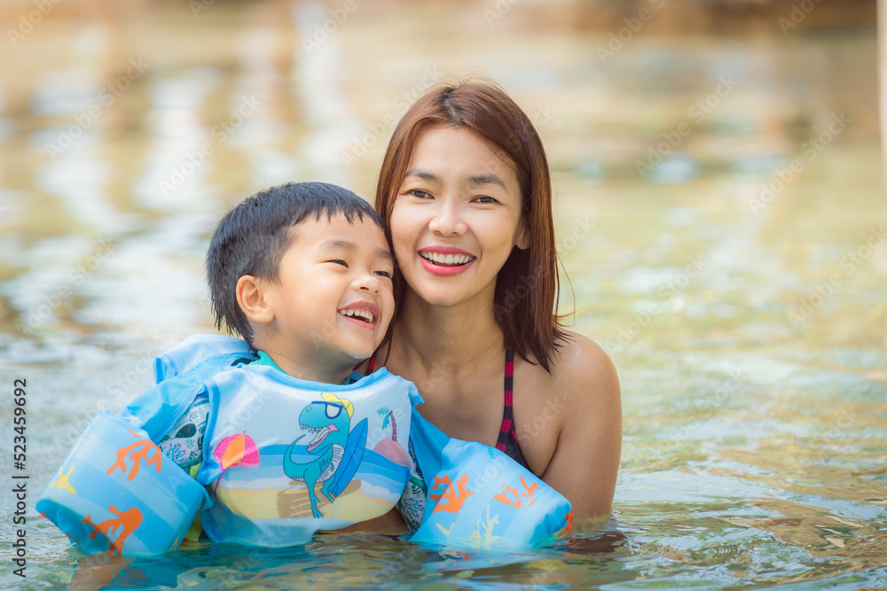 Little boy with mom relaxing in a swiming pool