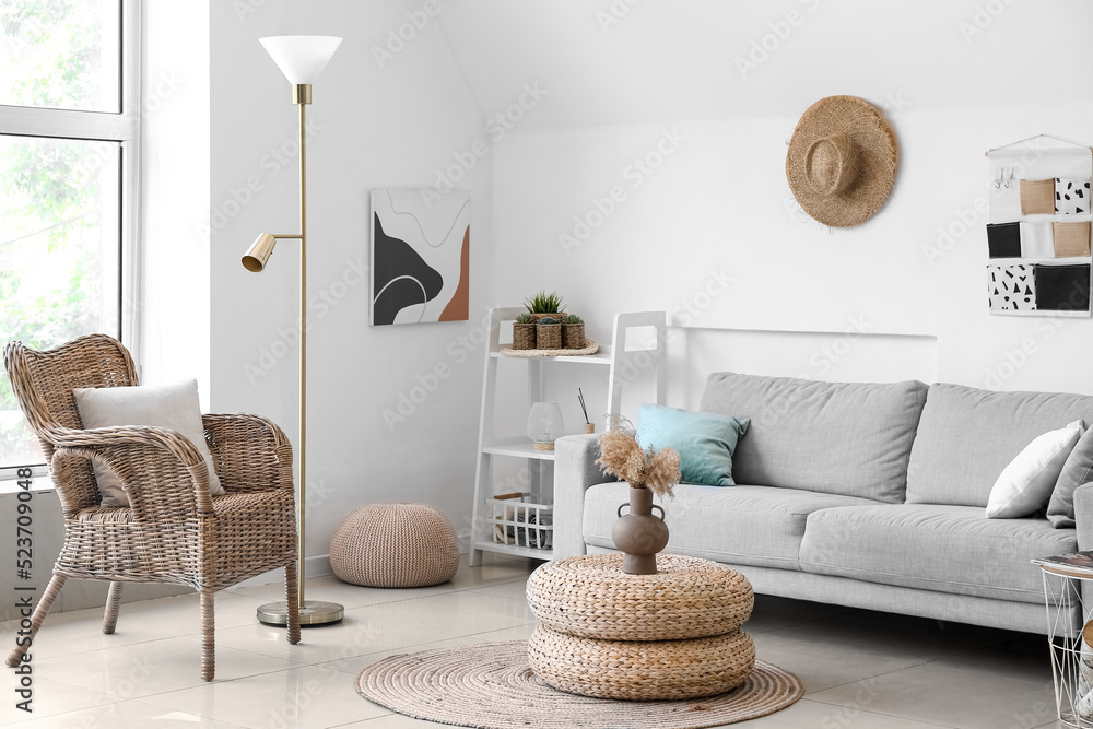 Interior of cozy living room with rattan poufs, armchair and sofa