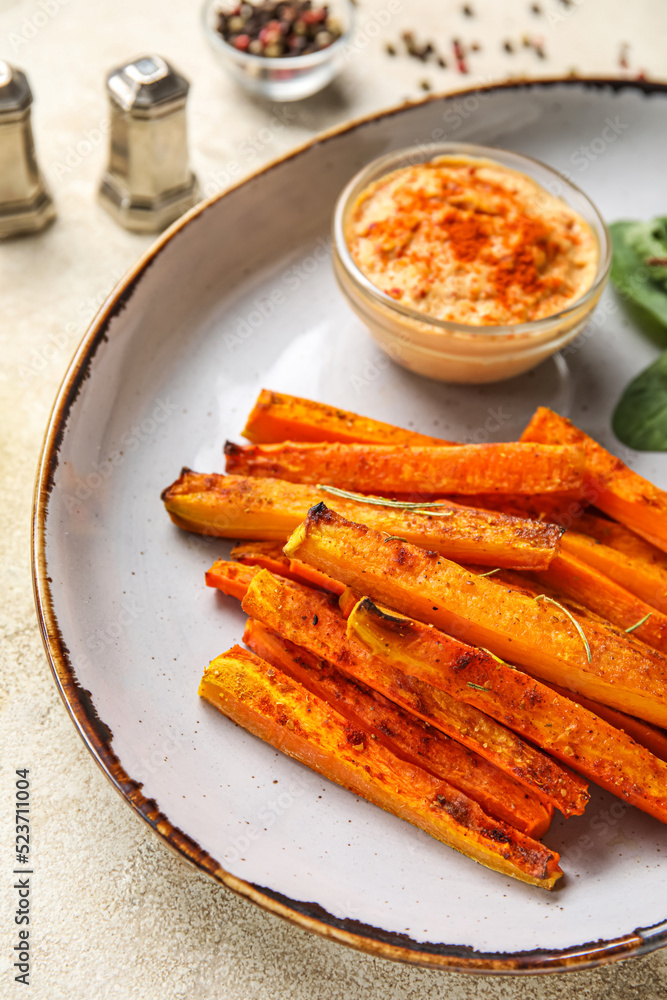 Plate of tasty baked carrots and sauce on table, closeup