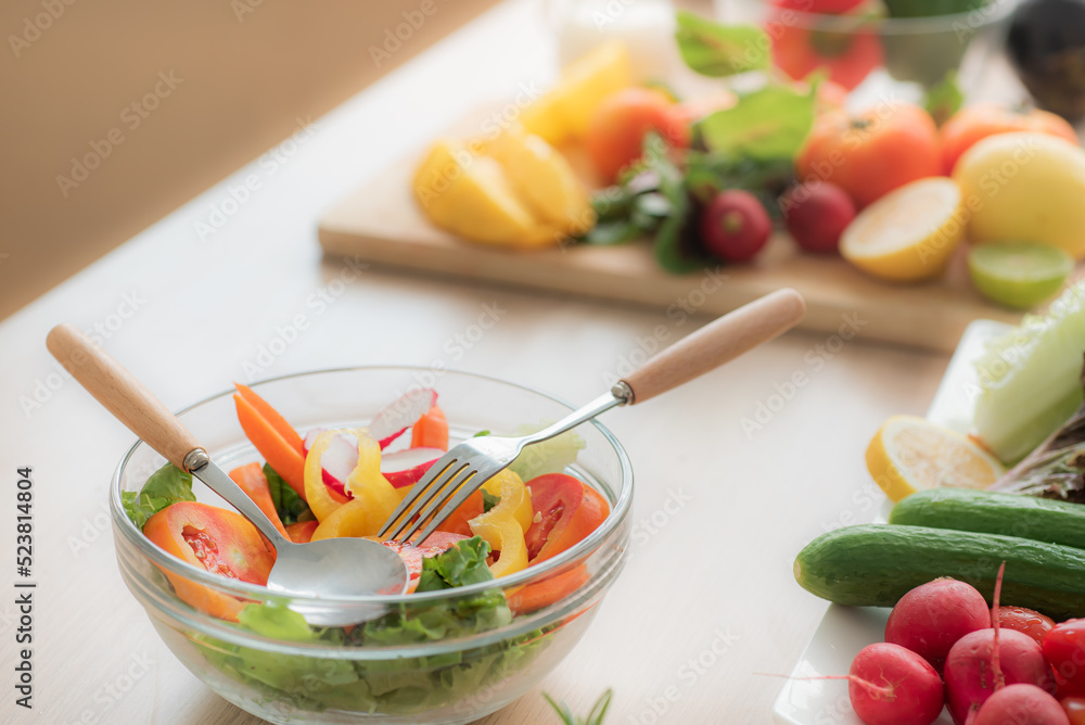 Vegetable salad in clear glass bowl and cutlery On the kitchen table, there are vegetables and fruit