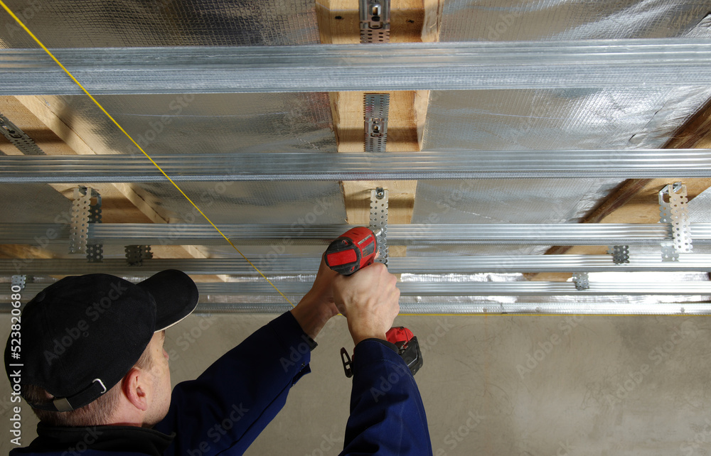 Builder installs profile metal frame for plasterboard ceilings