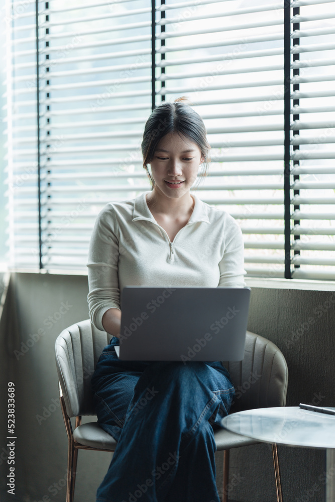 亚洲女人漂亮的年轻女人在办公室里用笔记本电脑工作。n在办公室里拿笔记本电脑工作