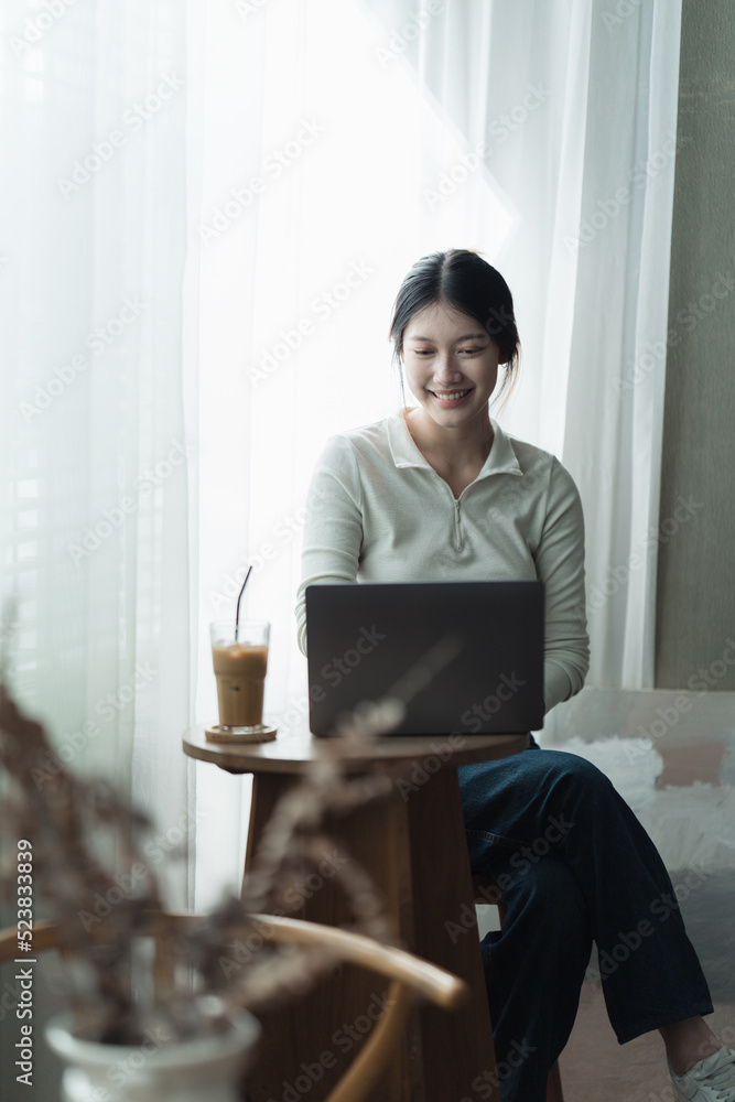 漂亮的年轻女人在办公室里用笔记本电脑工作。