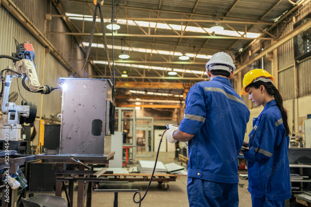 Caucasian male and Asian woman industrial work in manufacturing plant.