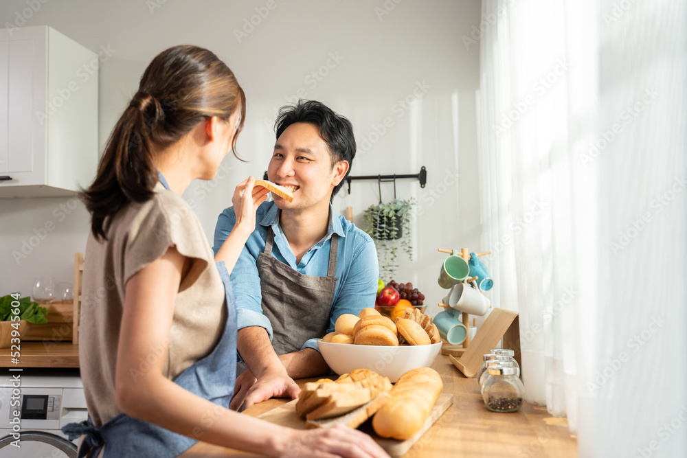 亚洲年轻女性在厨房里拿着面包给男性。