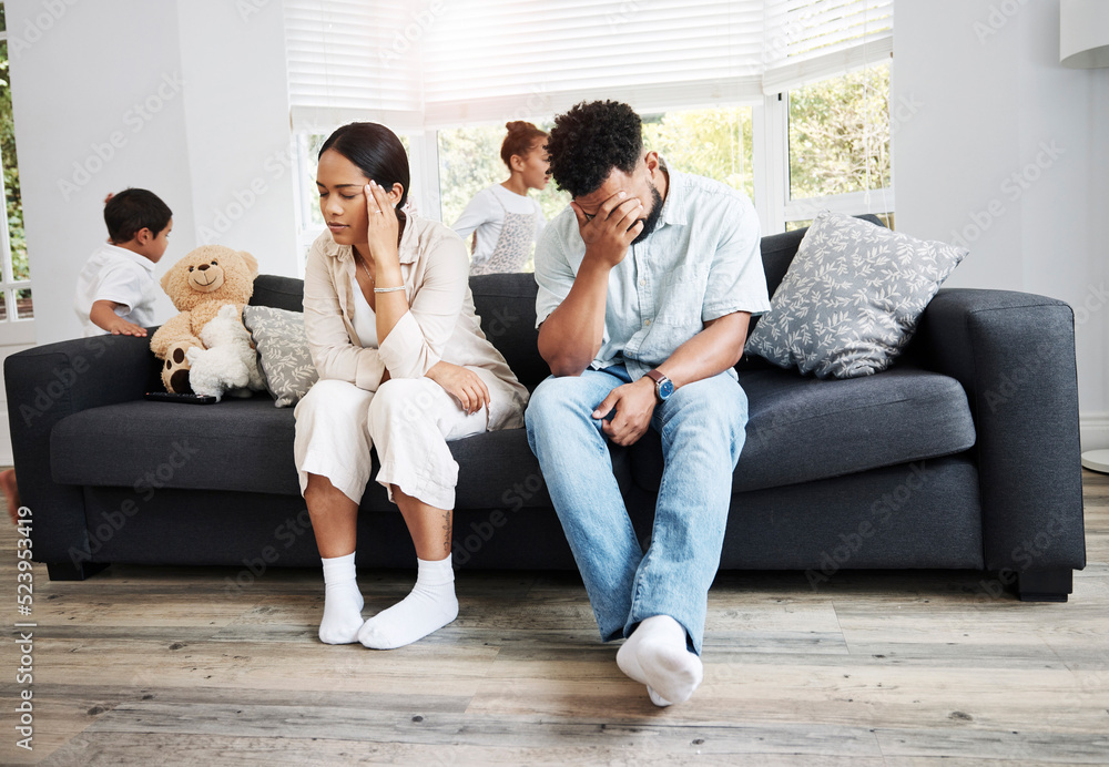 Sad, unhappy and stressed parents sitting on a couch near their children at home after an argument. 