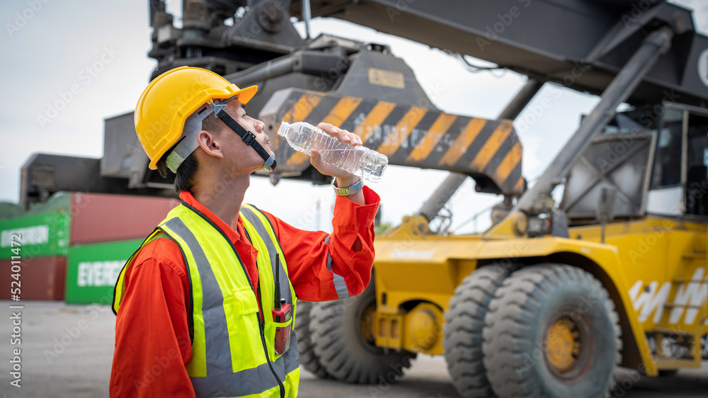 Foreman or worker is drinking a bottle of water after finishing work and relaxing on the old truck a