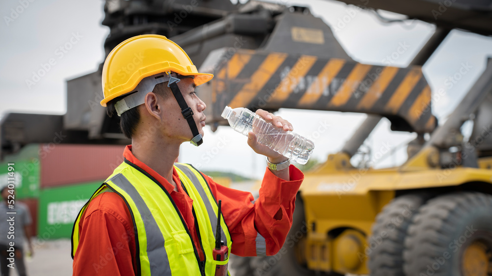 Foreman or worker is drinking a bottle of water after finishing work and relaxing on the old truck a