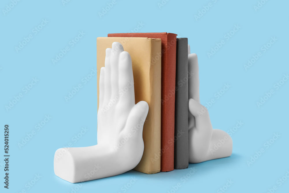 Books with stands in shape of hands on blue background