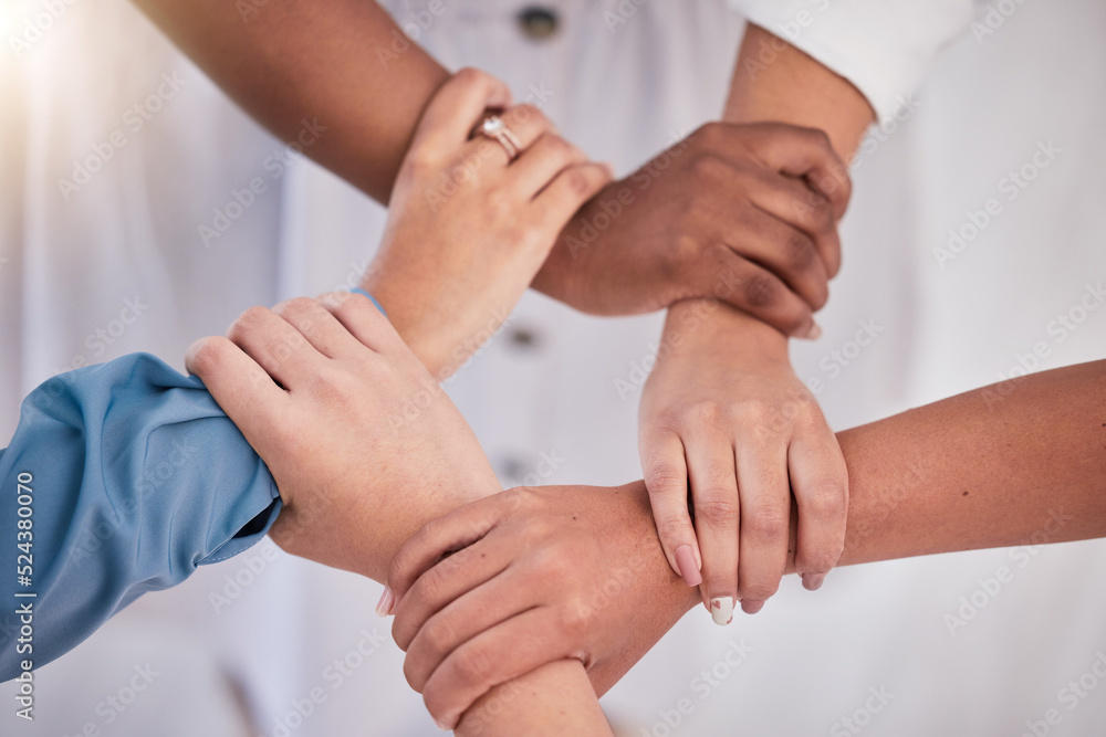 Diverse colleagues hands holding wrists from above in support of unity, loyalty and teamwork in the 