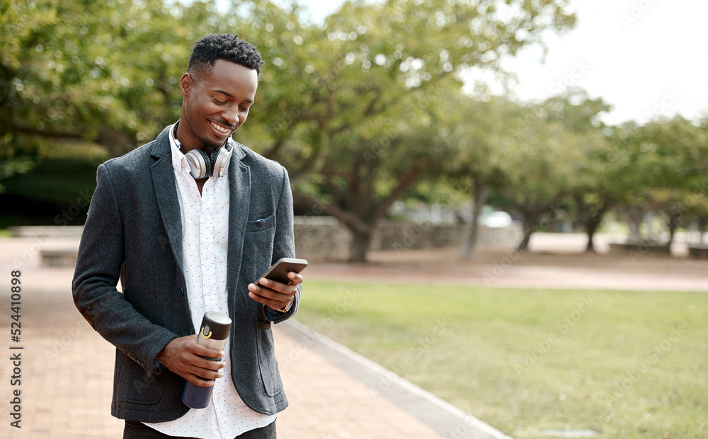 Young, cool smiling businessman on a phone having a walk in the park outside in nature. Happy man te