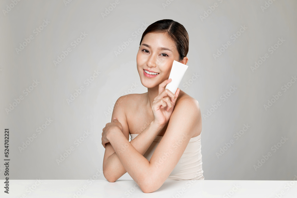 Ardent woman smiling holding mockup product for advertising text place, light grey background. Conce