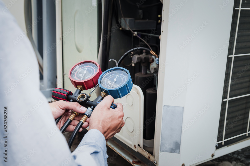 Mechanic  air conditioner technician is using a manifold gauge to check the refrigerant in the syste