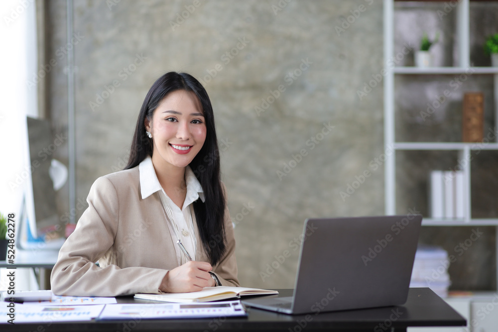 Portrait of a charming beautiful young business woman in the office working on a laptop and financia