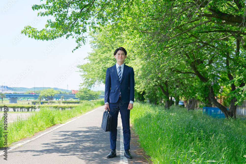 新緑の中に立つビジネスマンの全身のポートレート