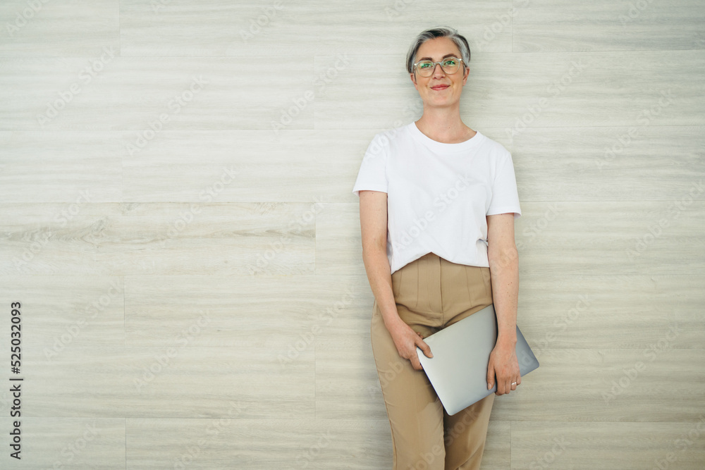 Cheerful businesswoman standing against a wall in an office