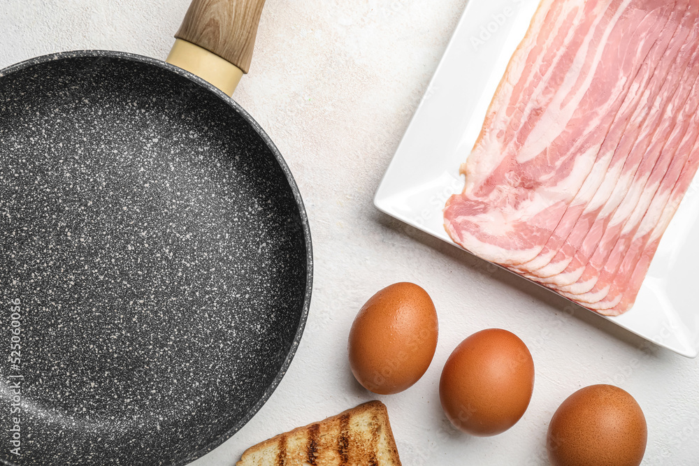 Frying pan, raw bacon and eggs on light background, closeup