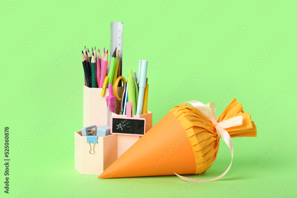 School cone and holder with stationery on green background