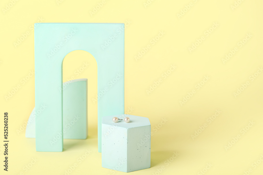 Showcase pedestal with stylish pearl earrings on color background