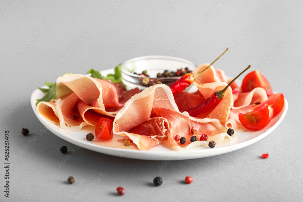 Plate of delicious jamon and peppercorns on light background