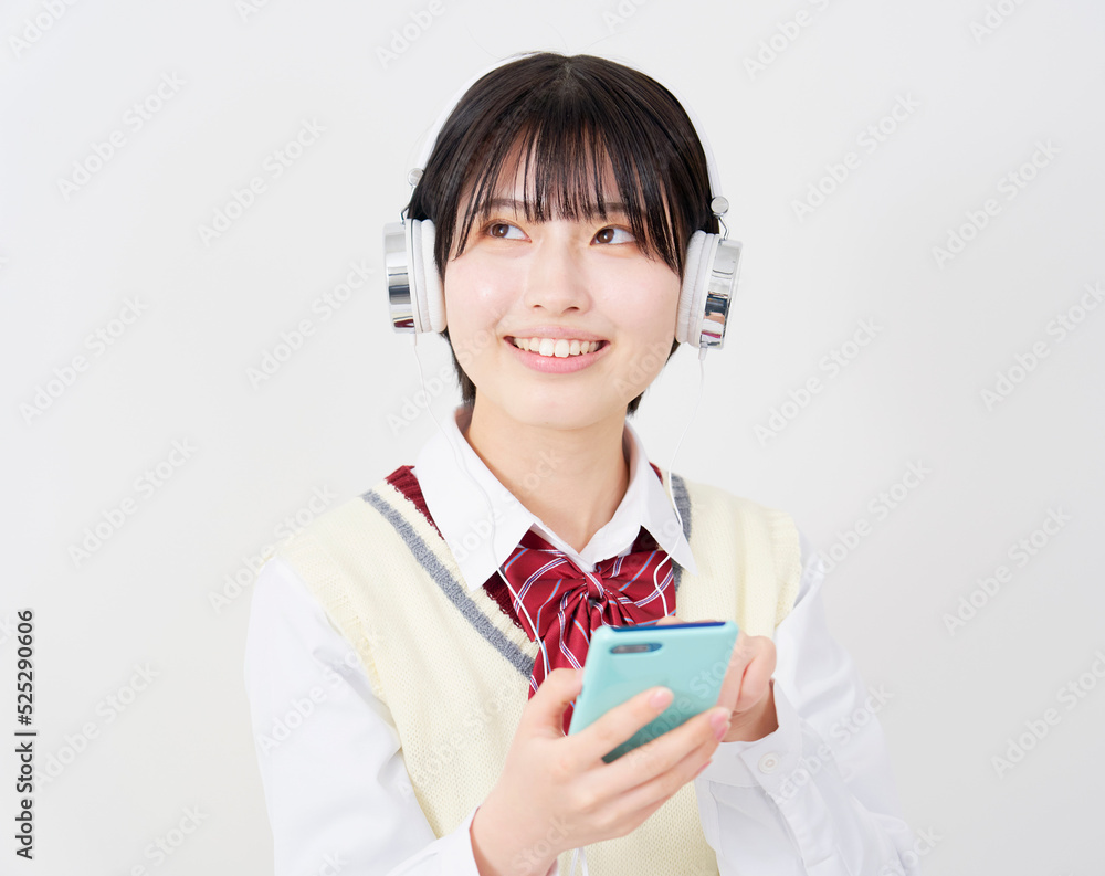 白背景でスマホを持ってヘッドホンで音楽を聴く女子高生