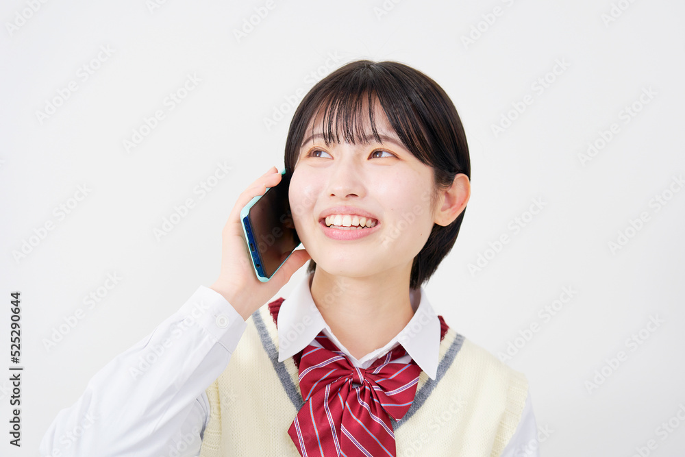 白背景でスマホで電話をする女子高生