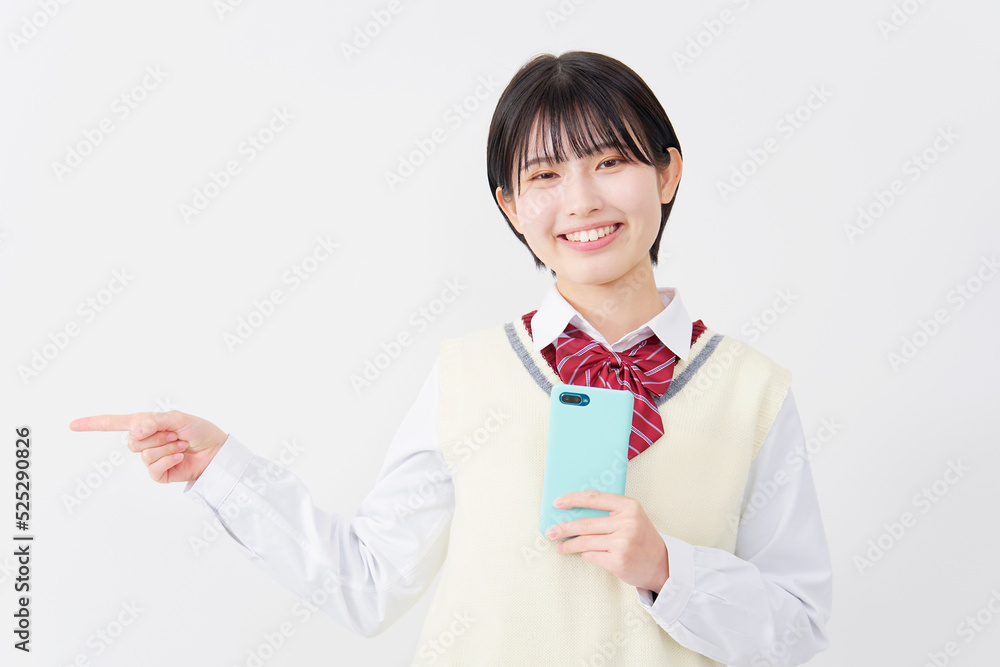 白背景でスマホを持って左を指差す女子高生