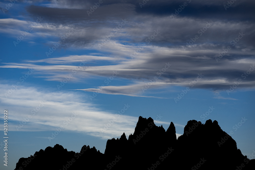 Mountain skyline on horizon. Dark silhouette of mountains against blue and dramatic sky with grey cl