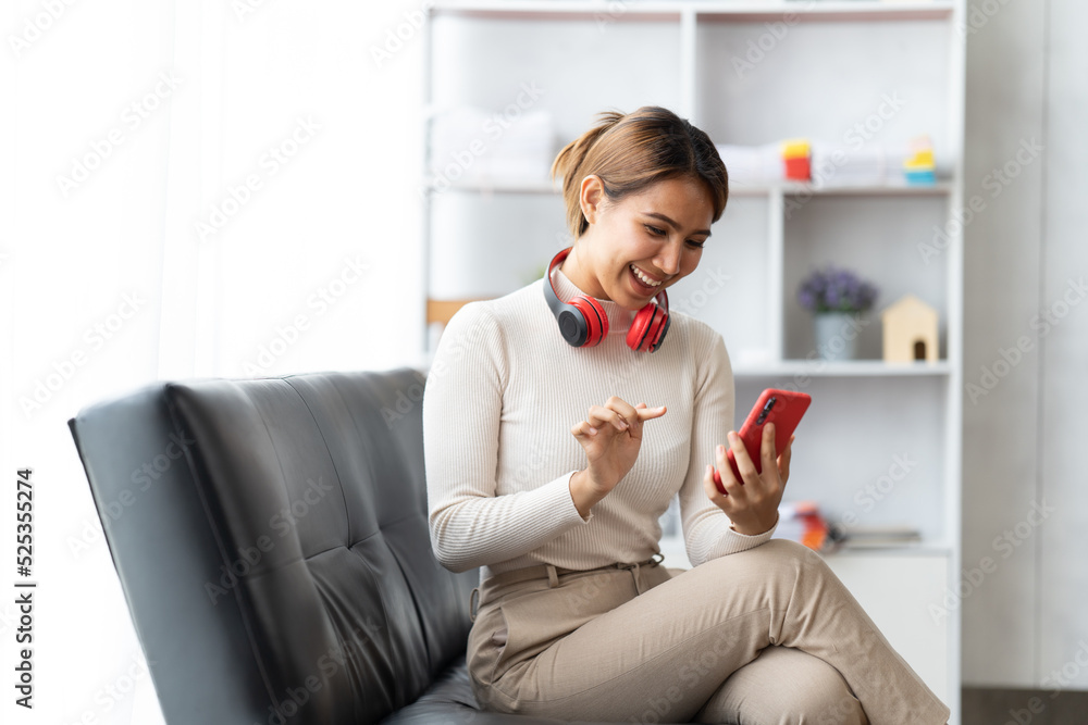 Happy young woman using smartphone at home sitting on soft couch, she is using a smartphone and text