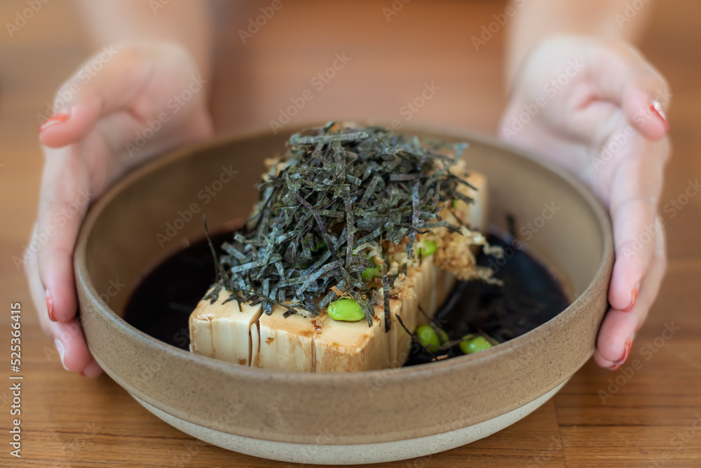 特写一道冷豆腐，配大士酱油，将海藻和毛豆放在日式陶器中