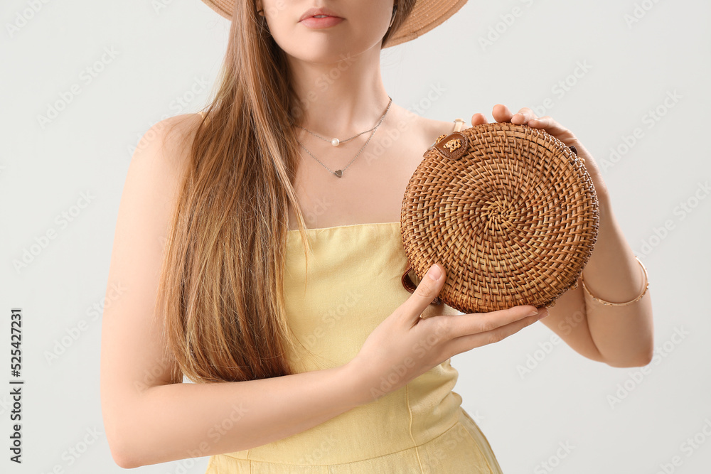 Woman holding stylish rattan handbag on light background, closeup