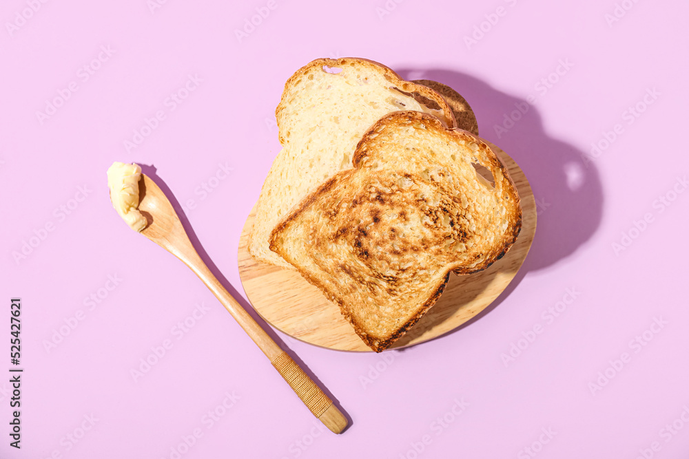 Wooden board of toasts and spoon with butter on pink background