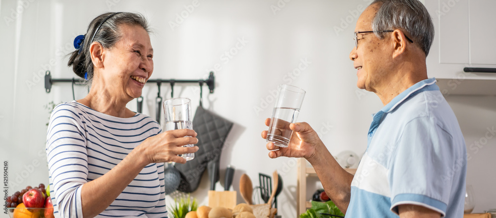 亚洲一对老年夫妇在家里的厨房里喝了一杯水。