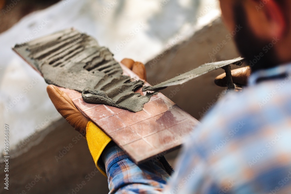 A worker with gloves lays down and dismantles the ceramic tiles of the stairs