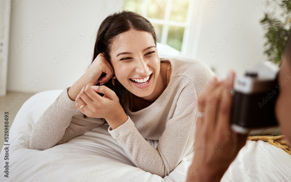 Beautiful, attractive and happy woman having a home photoshoot while lying in bed and smiling. Young