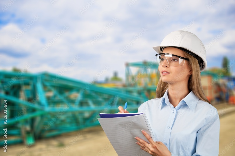 A young woman mine worker wearing protective wear with equipment in the background